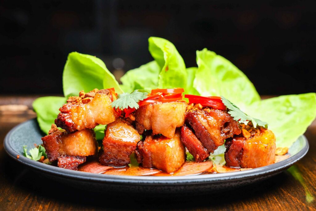 Glazed bites with greens in a black serving bowl at 440 Main.